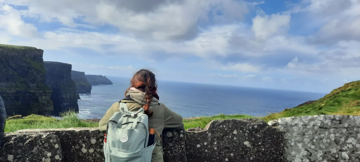 Schülerin schaut übers Meer und Klippen in Irland